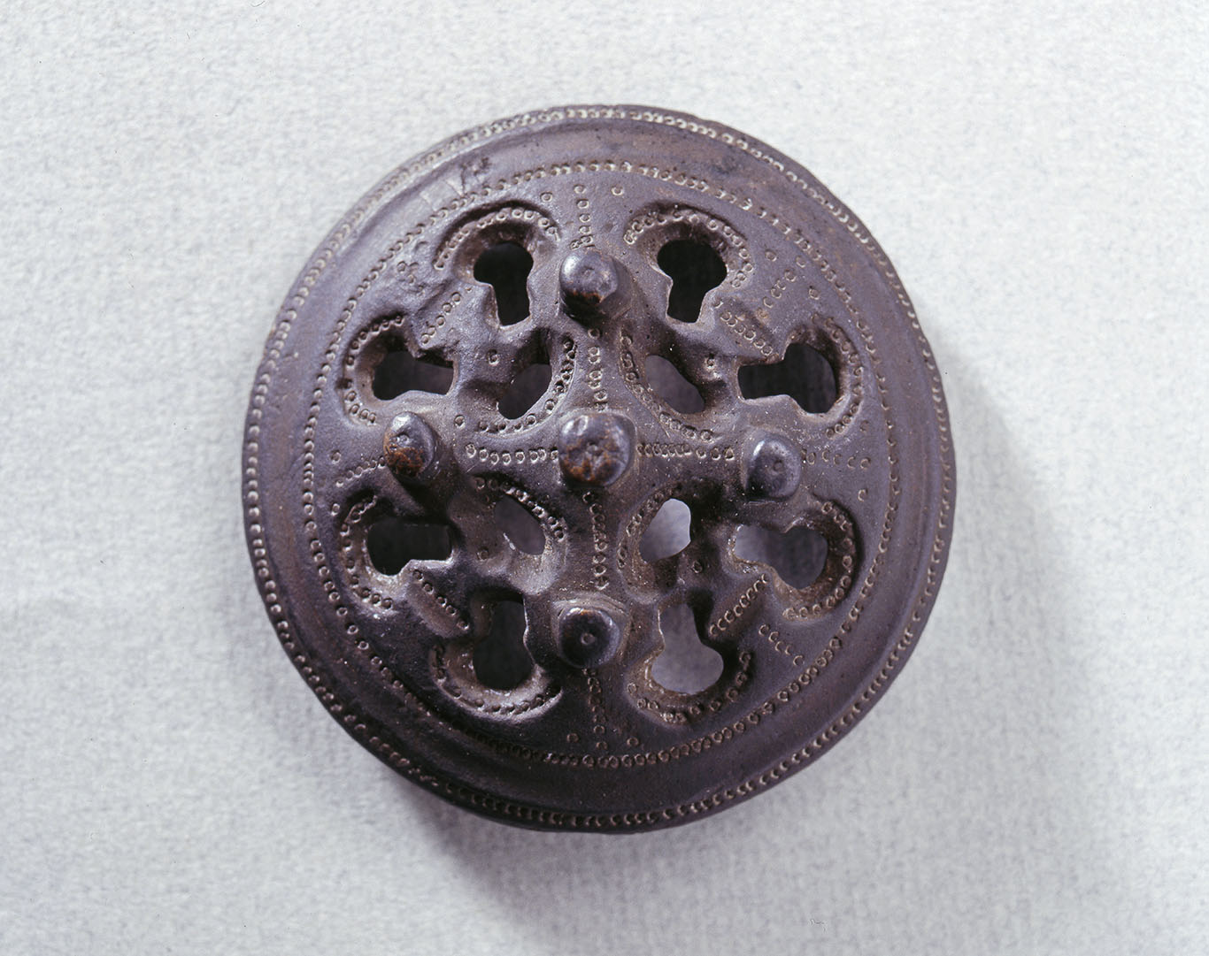 Lieksan Multiniemestä löydetty ruskea pyöreä kupurasolki. Soljessa on paljon pyöreitä kuviointeja ja yksityiskohtia. Kuva: Museovirasto.