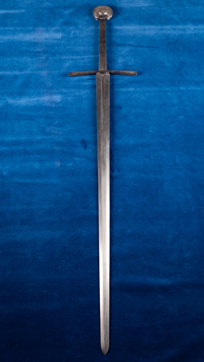 Valtimosta löytyi rautakautinen miekka 1800-luvun lopulla. Kuvasssa näkyvä miekka on seppämestarin tekemä tarkka kopio esineestä. Miekka on kiiltävän harmaa ja seon sinisellä taustalla. Kuva: Henna Palovaara